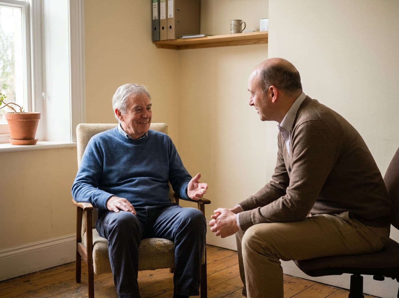 A urologist talking with an older male patient in a small exam room